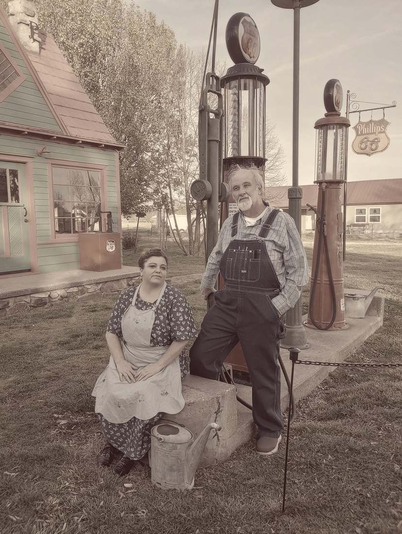 Two cast members posing by vintage Phillips 66 gas pumps (sepia)