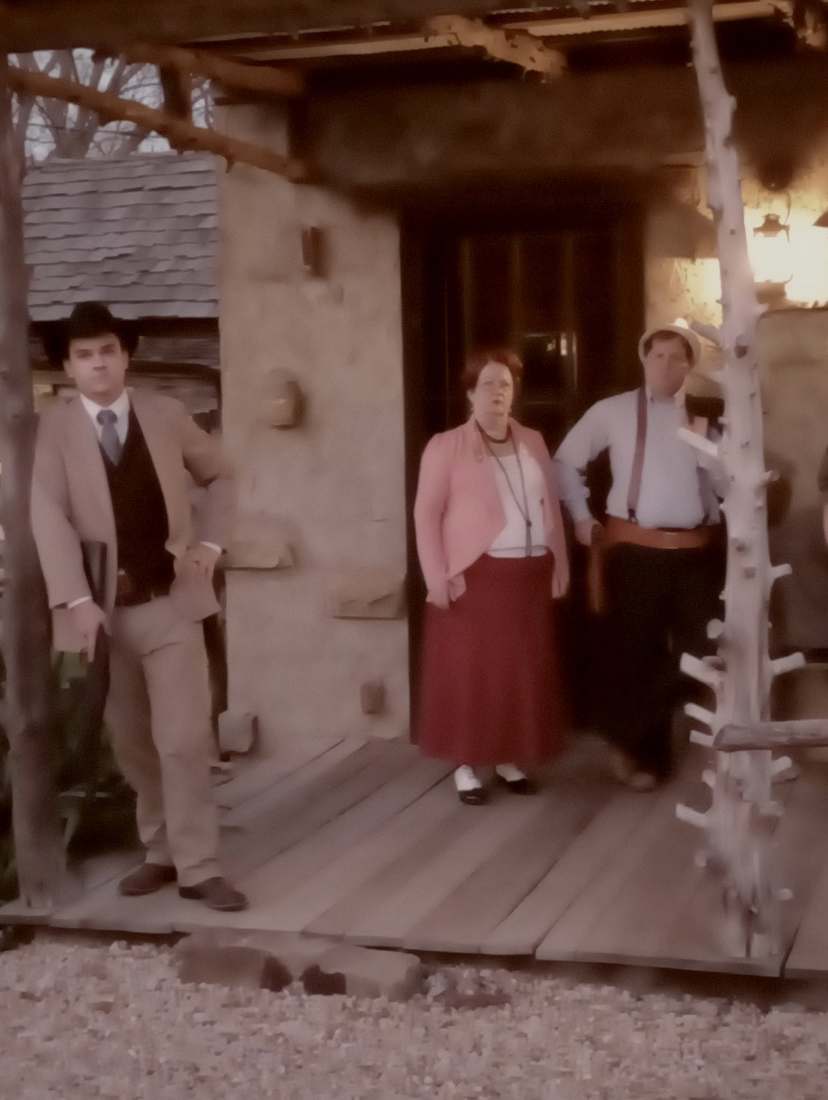 Three cast members standing in the doorway of the marshal's office