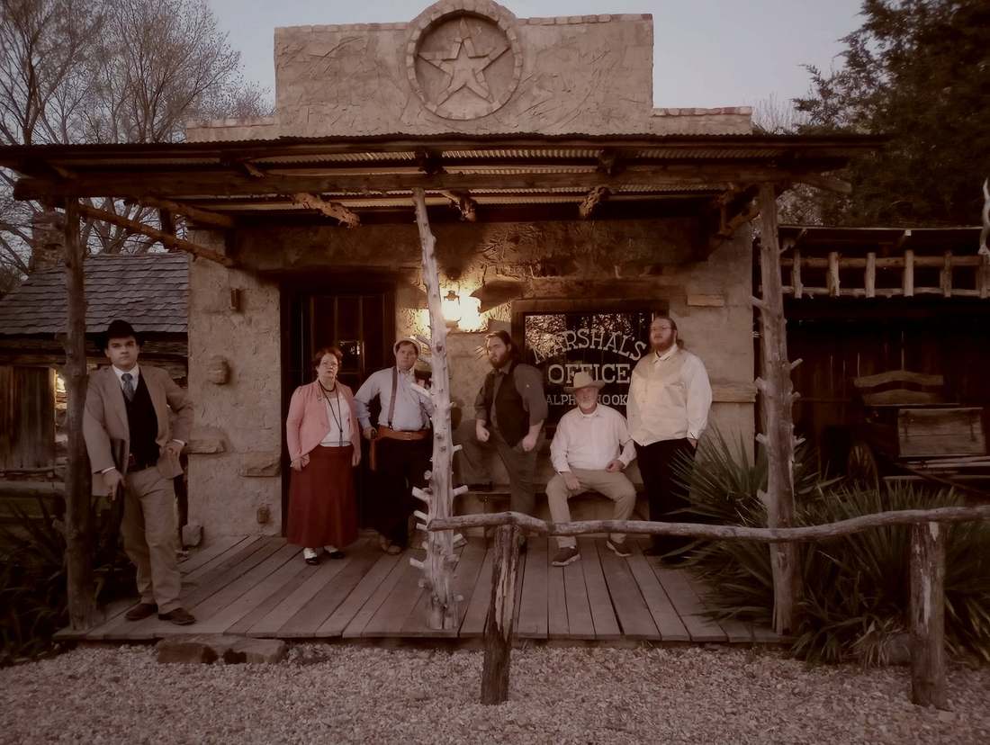 Six cast members on the marshal's office porch at dusk