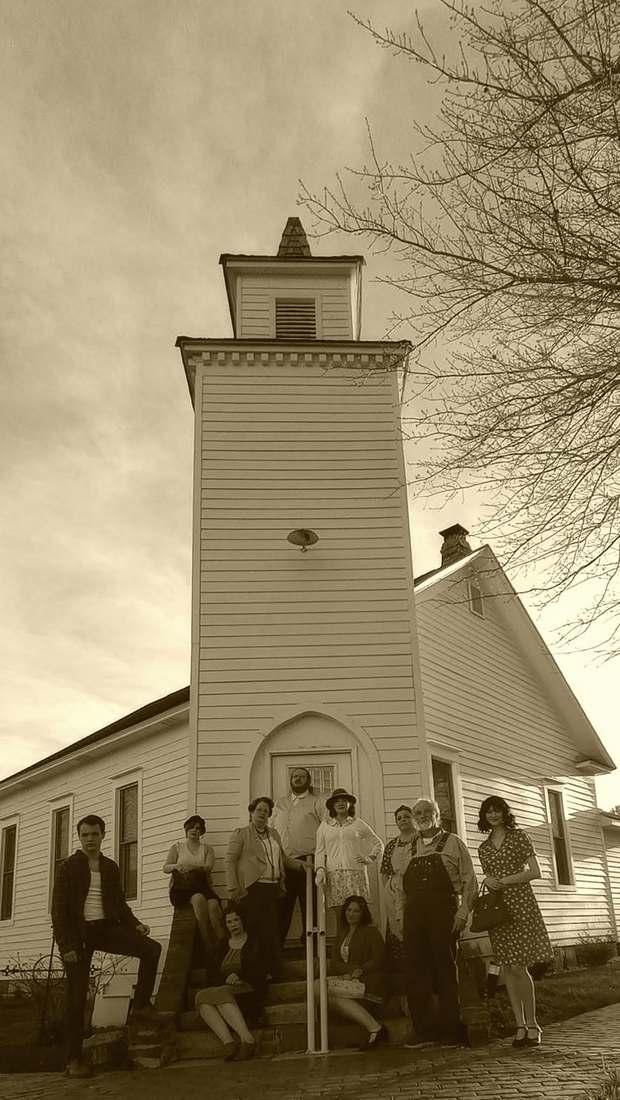 The company posed on the steps of a tall white church (sepia)