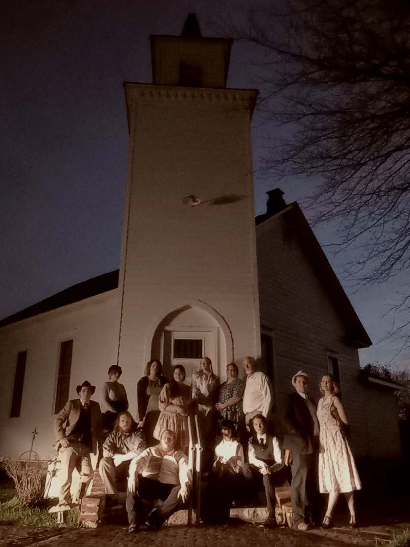 The Bonnie & Clyde company posed on the steps of the tall white church at night (sepia)