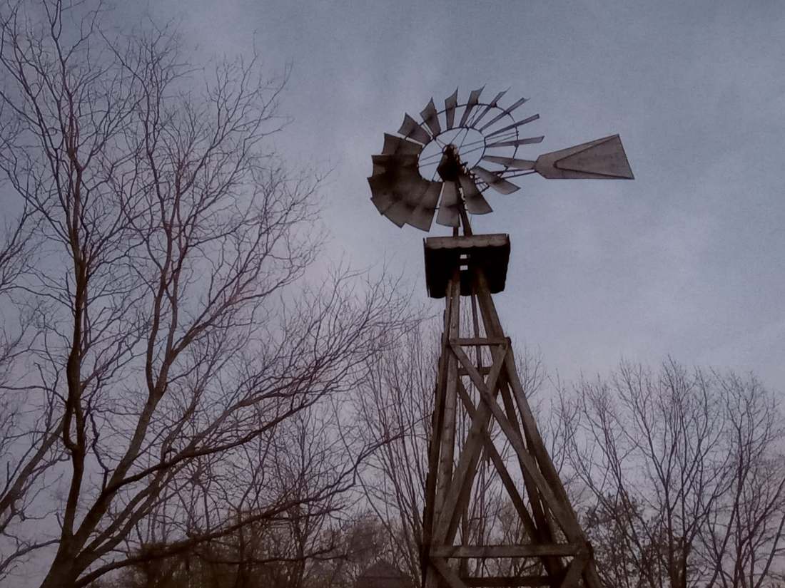 A farm windmill silhouetted against a dusky sky