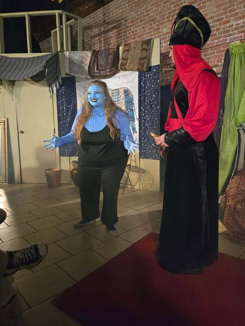 The blue Djinn spreads her arms wide before the Vizier in Twisted