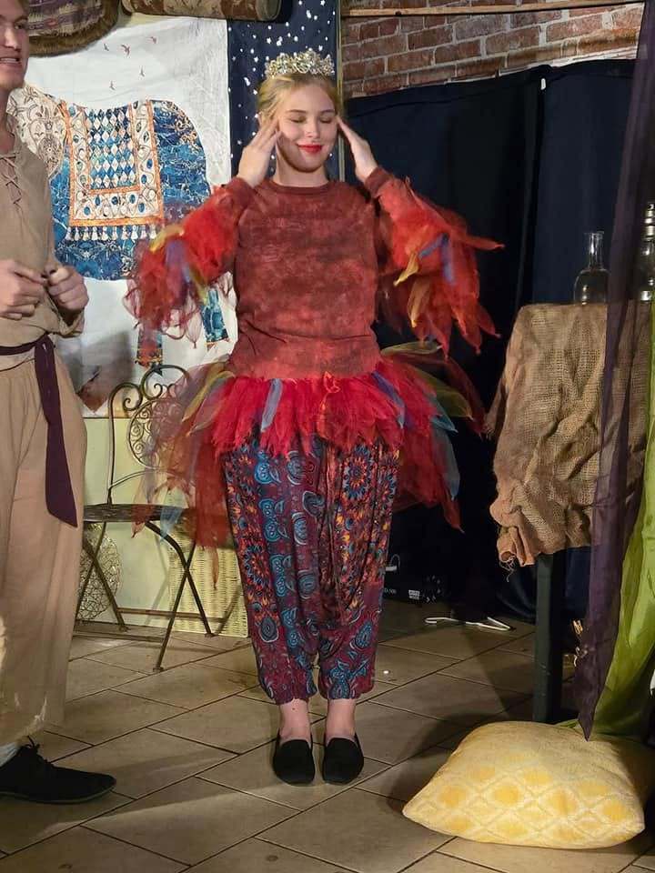 Iago in a red feathered costume and crown on the Twisted set