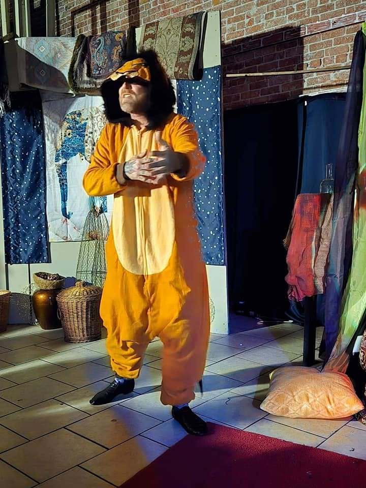 A performer in an orange tiger suit clasps their paws on the Twisted stage