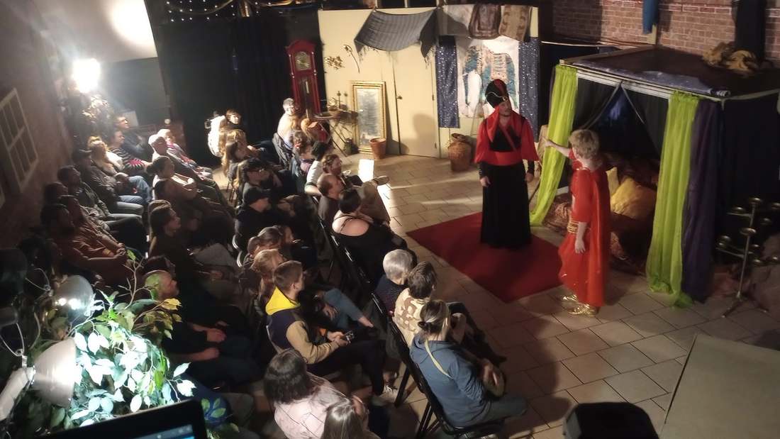 The Vizier presents a storyteller in a red gown to the house in Twisted