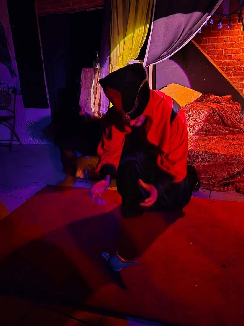 The Vizier kneels on the red carpet in a wash of purple light in Twisted