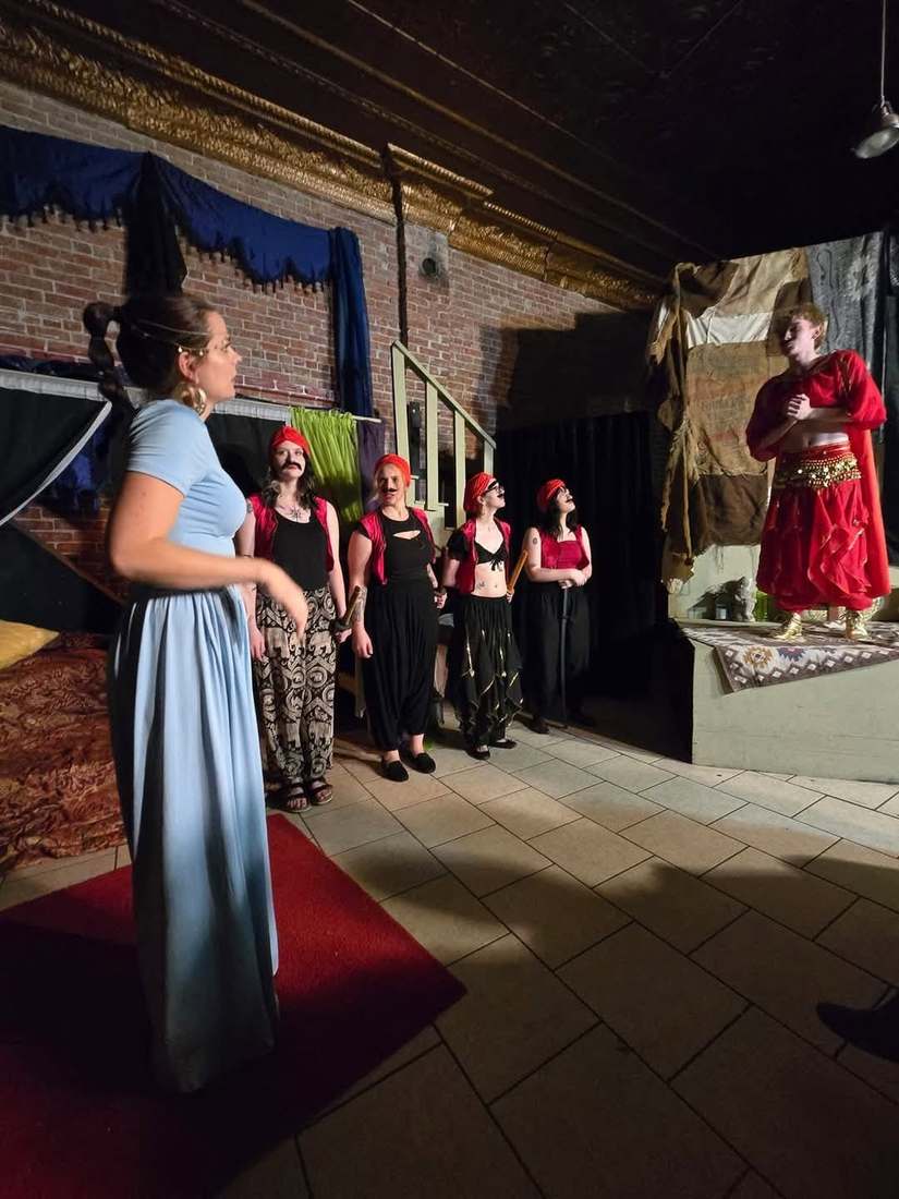 The princess faces a line of red-capped ensemble players in Twisted