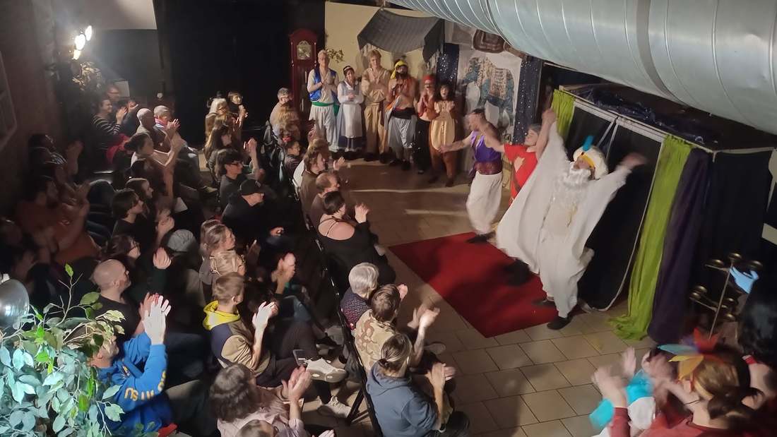 A performer in a flowing white cape bows at the Twisted curtain call