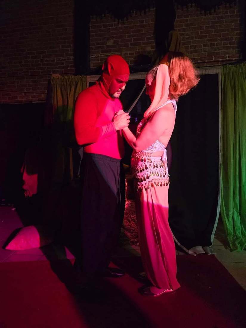 The pair bows their heads together under pink light in Twisted