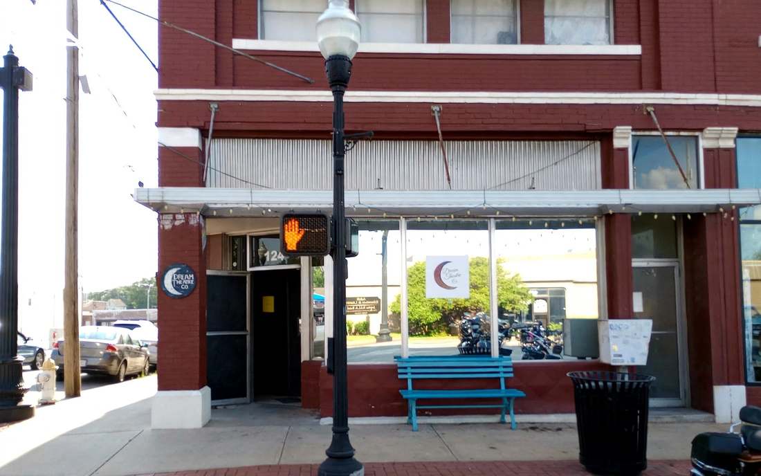 The front exterior of Dream Theatre Co. at 124 S Main St in downtown Joplin — red brick storefront with the crescent moon signs, the 124 door, and an empty sidewalk